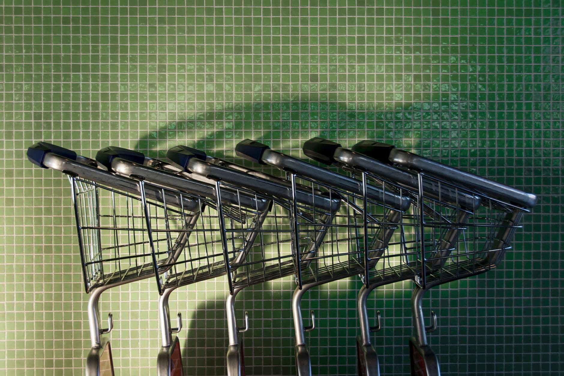 A shopper with a partially filled grocery cart in a supermarket aisle