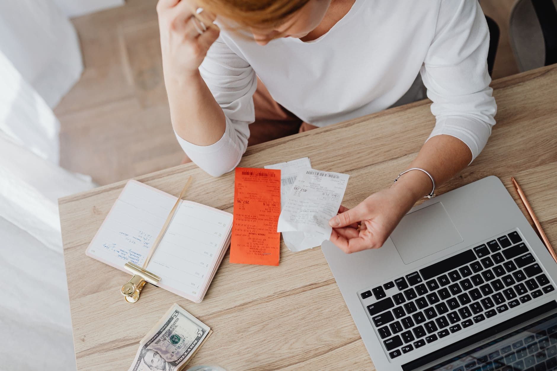 Young adult reviewing bills and loan paperwork at a laptop