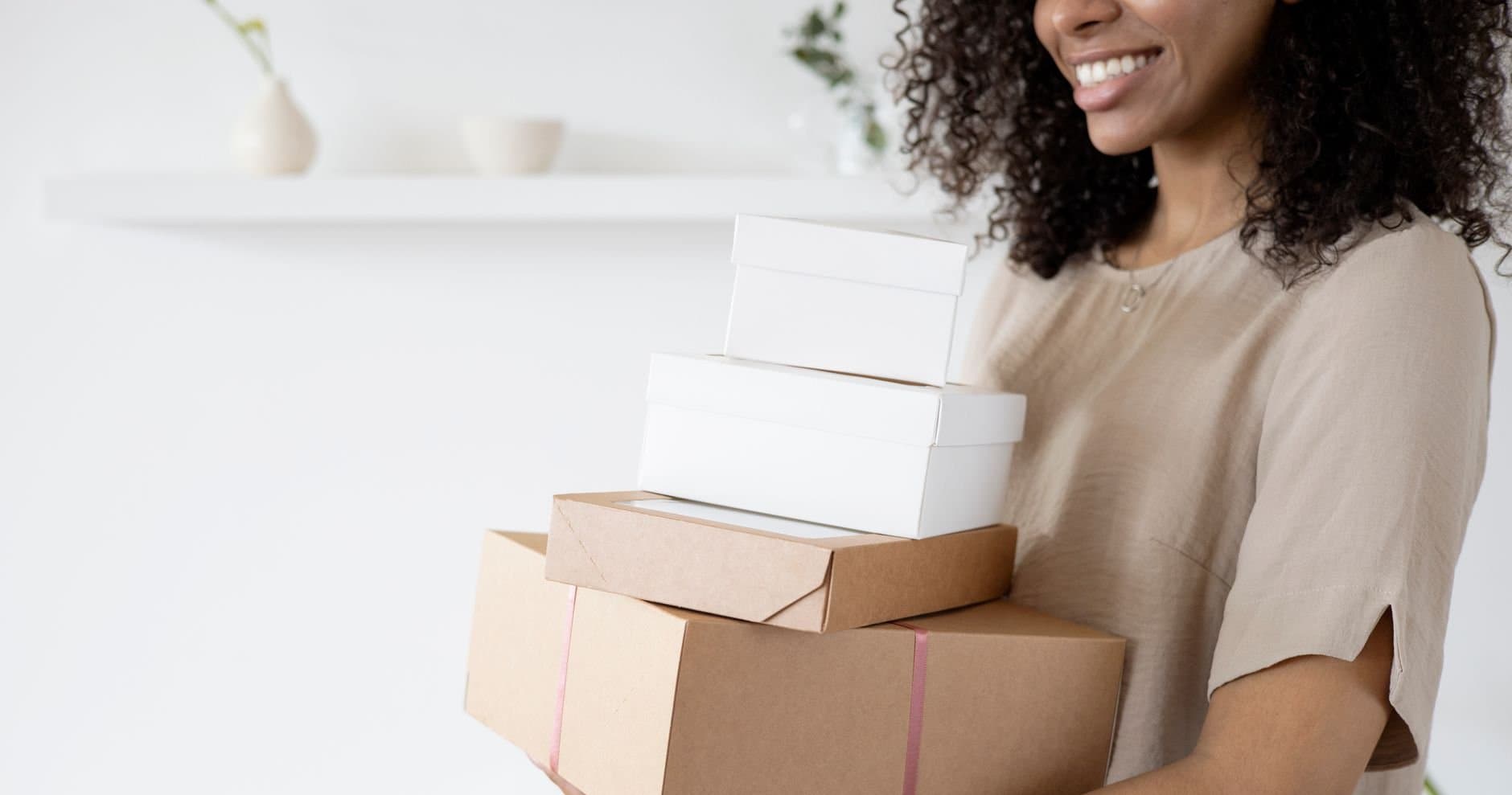 A small business owner holding stacked shipping boxes
