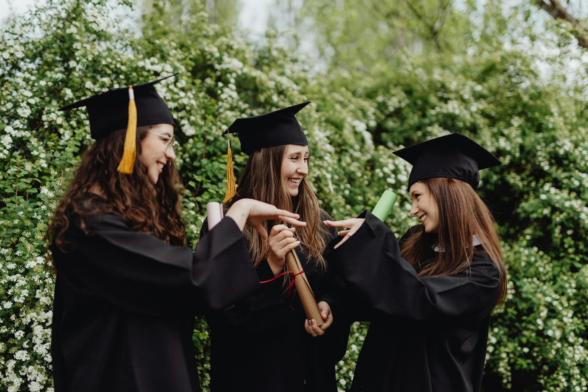 College graduate in cap and gown holding diploma with student loan paperwork