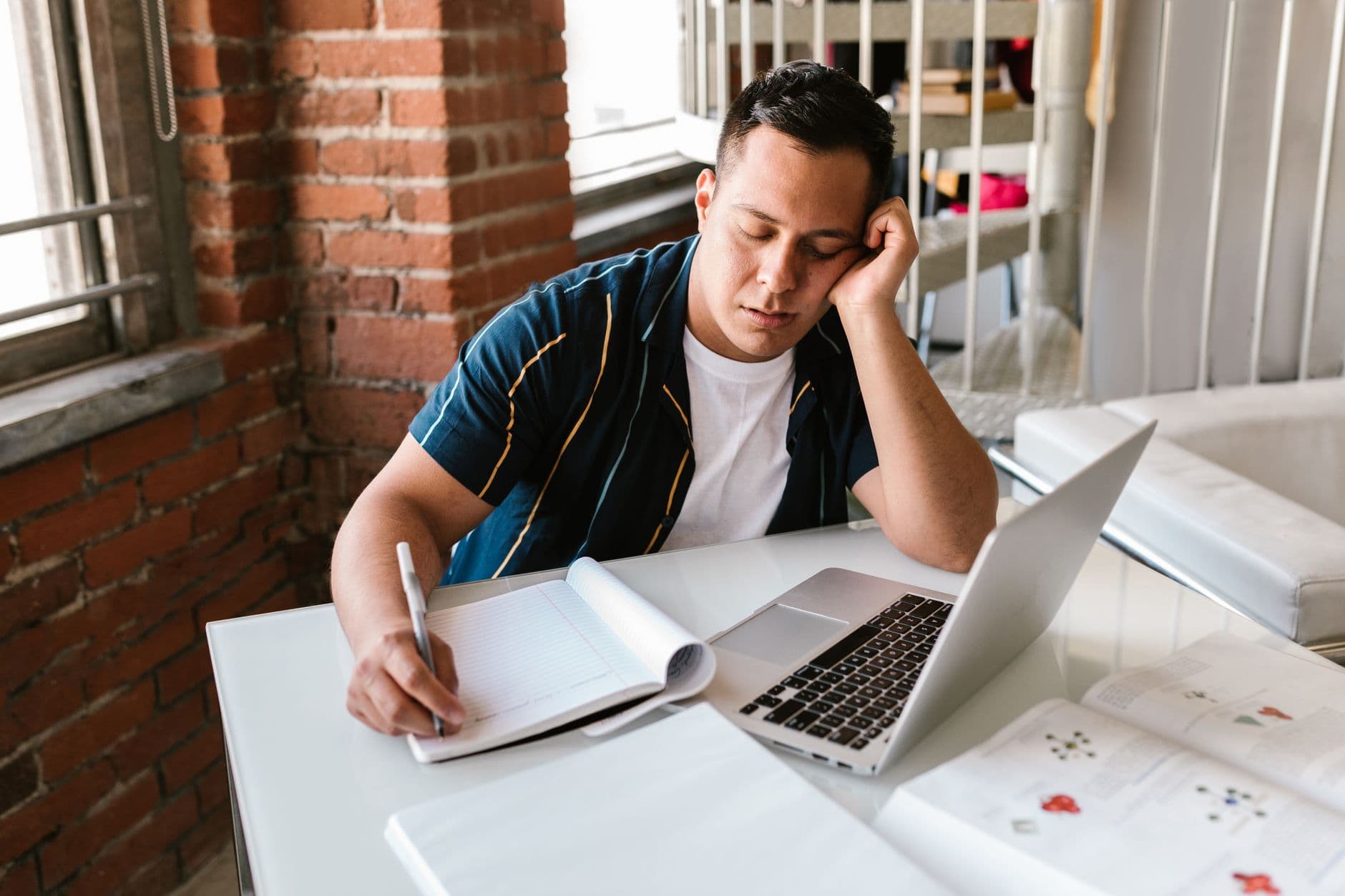 A young student looking stressed while working on a laptop at a desk
