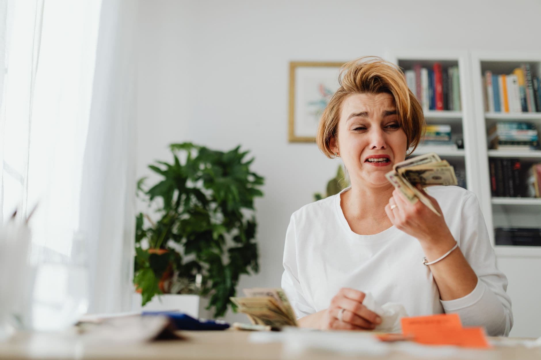 A stressed adult reviewing bills and student loan paperwork at a kitchen table