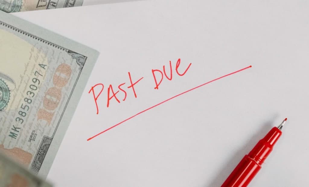 Past due notice written in red on paper next to a $100 bill