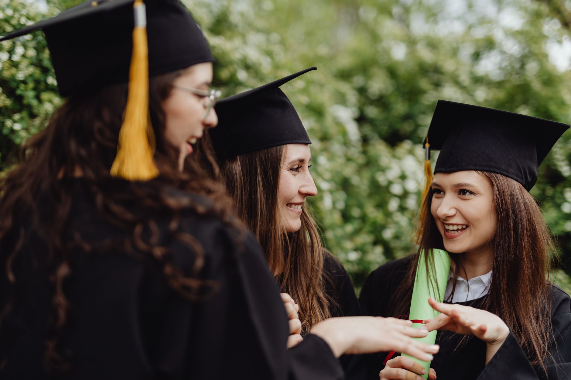 College graduate in cap and gown holding diploma with student loan paperwork