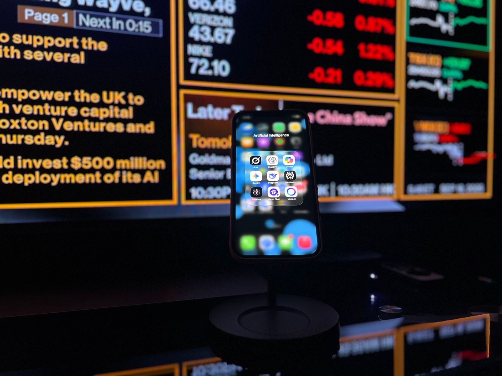 Smartphone displaying AI apps in front of a financial data screen